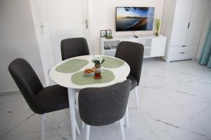 mesa blanca con sillas negras y TV en Art Life apartments (Olive), en Alanya