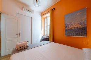 a bedroom with a white bed with an orange wall at Appartement Claudia - Central - Very close to Sea - Calm - AC in Nice