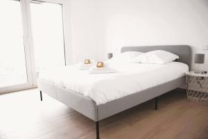 a white bedroom with a large bed with white sheets at Beautiful Stylish 2BR Apartment in Kirchberg in Luxembourg