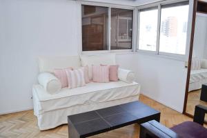 sala de estar con sofá blanco y almohadas rosas en Libertador 2785 by depptö in 