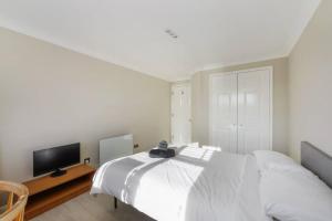 um quarto branco com uma cama e uma televisão em Luxury Apartment in Kingston em Kingston upon Thames