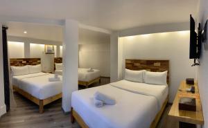 ボラカイにあるEl Puerto Boracay Shoreのホテルルーム 白いシーツ付きのベッド2台付