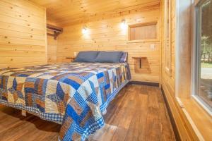 a bedroom with a bed in a wooden cabin at The Blue Devil Cabin #5 at Blue Spruce RV Park & Cabins in Tuckerville