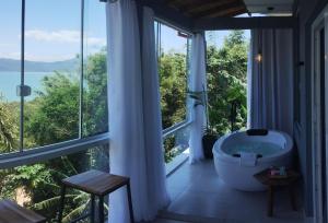 uma casa de banho com uma banheira em frente a uma janela em North Suíte em Florianópolis