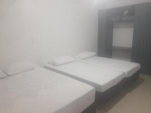 2 łóżka w małym pokoju z białą pościelą w obiekcie Hub House w mieście Kurytyba