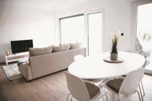 a white living room with a table and a couch at Beautiful 2BR Apartment in Kirchberg in Luxembourg