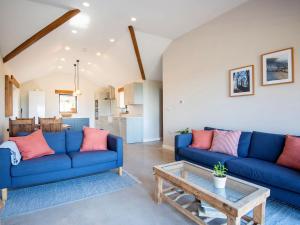 una sala de estar con sofás azules y una mesa. en Appletree Barn, en Lower Soudley