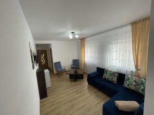 sala de estar con sofá azul y ventana en Cazare apartamente LAVI-TOUR Tg Neamț en Tîrgu Neamţ