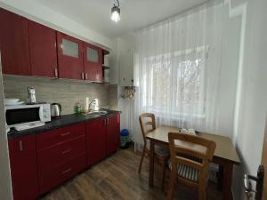una cocina con armarios rojos y una mesa con sillas. en Cazare apartamente LAVI-TOUR Tg Neamț en Tîrgu Neamţ