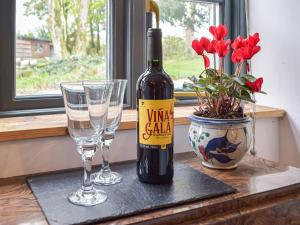 a bottle of wine and two glasses on a table at Cwtch Wrth Plas - Uk45619 in Tal-gareg