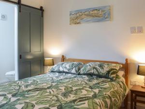 a bedroom with a bed with a green bedspread at Cwtch Wrth Plas - Uk45619 in Tal-gareg