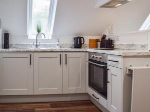 a kitchen with white cabinets and a sink and a window at The Loft At Tall Trees in Welton