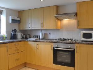 a kitchen with wooden cabinets and a stove top oven at Owl Cottage in Flamborough