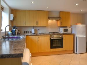 a kitchen with wooden cabinets and a white refrigerator at Owl Cottage in Flamborough