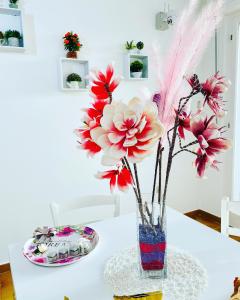 un vaso con fiori rossi seduto su un tavolo di B&b il cuore di Kroton a Crotone