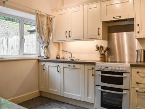 una cocina con armarios blancos y fregadero en Springwell en Near Sawrey