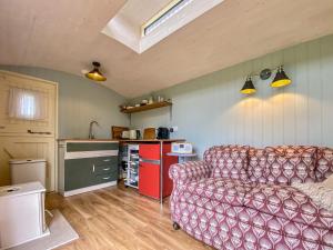 a living room with a couch and a kitchen at Ivy Shepherds Hut - Uk45590 in Seend