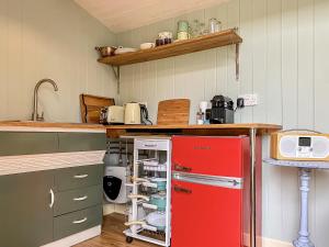 a kitchen with a red refrigerator in a kitchen at Ivy Shepherds Hut - Uk45590 in Seend