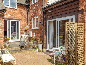 a brick house with a patio with a table and chairs at The Grooms Cottage-uk45659 in Bishops Castle