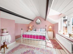 1 dormitorio con paredes rosas y techo blanco en The Grooms Cottage-uk45659 en Bishops Castle