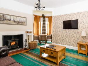 a living room with a fireplace and a tv at Gatehouse Lodge in Moulin