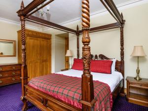 a bedroom with a four poster bed with red pillows at Gatehouse Lodge in Moulin