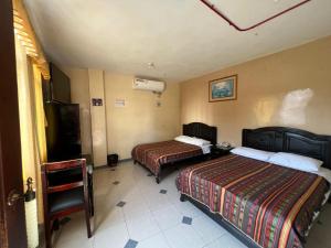 a hotel room with two beds and a tv at Hotel RODEY in Huaquillas