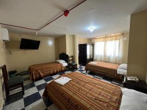 a hotel room with two beds and a tv at Hotel RODEY in Huaquillas