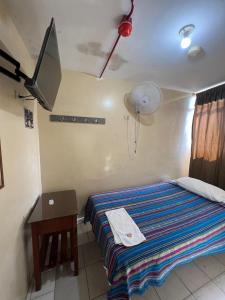 a bedroom with a bed with a desk and a tv at Hotel RODEY in Huaquillas