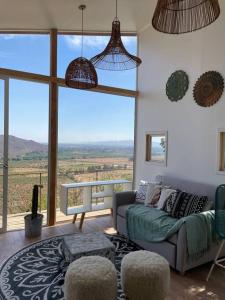 een woonkamer met een bank en een groot raam bij Cabaña del Boldo, naturaleza y vista al valle. in Curicó