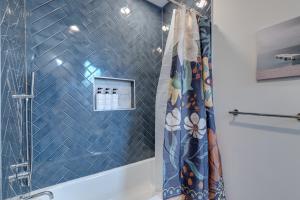 La salle de bains est pourvue d'une douche et d'un mur carrelé bleu. dans l'établissement Family Fun South Philly Game House Near Sports Stadiums and Concerts, à Philadelphie