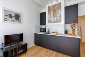 a kitchen with a counter and a tv in it at Designer apartment on St Louis Island in Paris - Welkeys in Paris