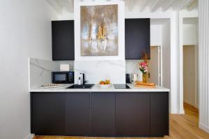 uma cozinha com um balcão preto e branco em Designer apartment on St Louis Island in Paris - Welkeys em Paris