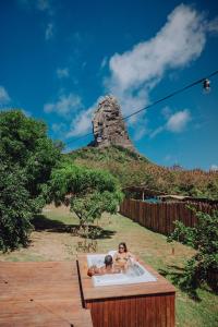 two people in a bath tub with a mountain in the background at Casa Pé na Areia Noronha in Fernando de Noronha