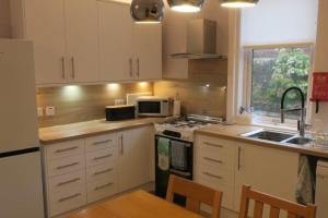 una cucina con armadi bianchi e piano cottura di Cumbrae View House (Licence no NA00109F) a Largs