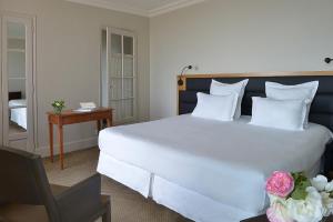 Un dormitorio con una gran cama blanca y una mesa en Grand Hotel de L'Océan, en Le Croisic