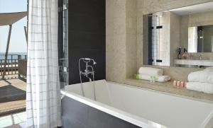 uma casa de banho com uma banheira e um espelho. em Grand Hotel de L'Océan em Le Croisic