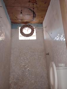 a bathroom with a toilet and a window at Suíte beija-flor in Camaçari