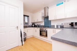 a kitchen with white cabinets and a wooden floor at Perfect Stay Rugby in Rugby