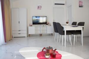 Una sala de estar blanca con una mesa y un televisor. en Art life apartments (PEONY), en Alanya
