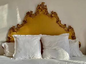 a bed with a gold head board and white pillows at Château La Bainerie in Tiercé