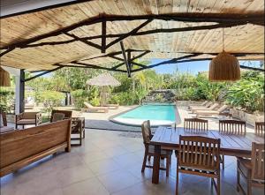 a patio with a table and chairs and a swimming pool at Villa with pool and tropical garden Madagascar in Marokindro