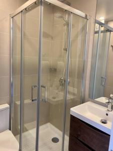 a shower with a glass door next to a sink at Disfruta Pucón caminando. Hermoso departamento in Pucón +3 photos