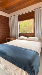 a bedroom with a large bed with a window at Chalés Requinte em Pedra Azul in Pedra Azul