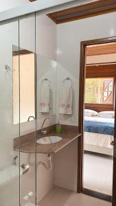 a bathroom with a sink and a mirror and a bed at Chalés Requinte em Pedra Azul in Pedra Azul