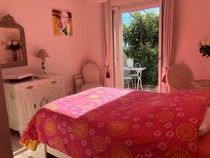 a pink bedroom with a bed and a window at A l'ombre du figuier in Lorgues