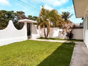 einen Hinterhof mit einem weißen Zaun und grünem Gras in der Unterkunft Casa Momo Bacalar in Bacalar