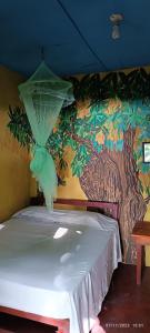 a bed in a room with a painting on the wall at Hostel La Gloria in Ometepe