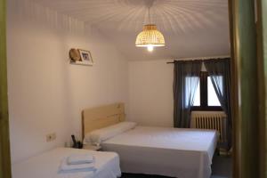 1 dormitorio con 2 camas y lámpara de araña en El Refugio Valdelinares Gastro Hostal, en Valdelinares