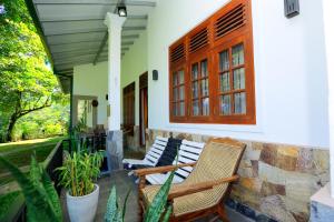 a porch with two chairs and a window at Estate Bungalow in Ratnapura